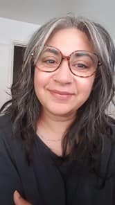 Rekha Kumar is wearing a black top and brown glasses