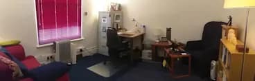 Room 1 has a burgundy sofa, a navy chair, a small office desk and chair and a grey filing cabinet